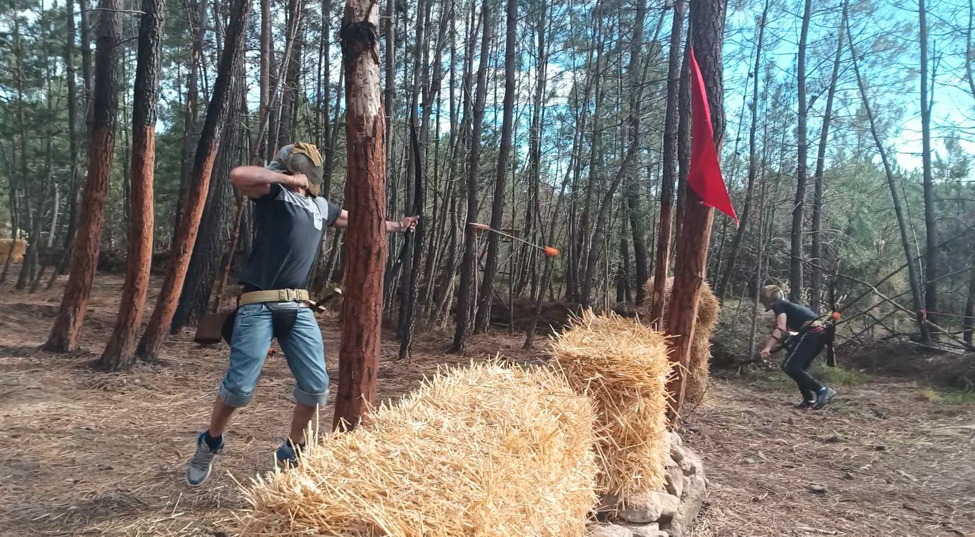 Archer qui tire en plein saut derrière des bottes de paille
